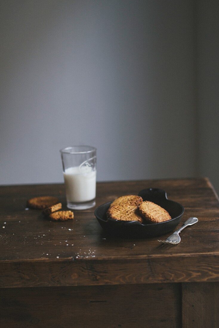 Freshly baked cookies and a glass of milk on a wooden table