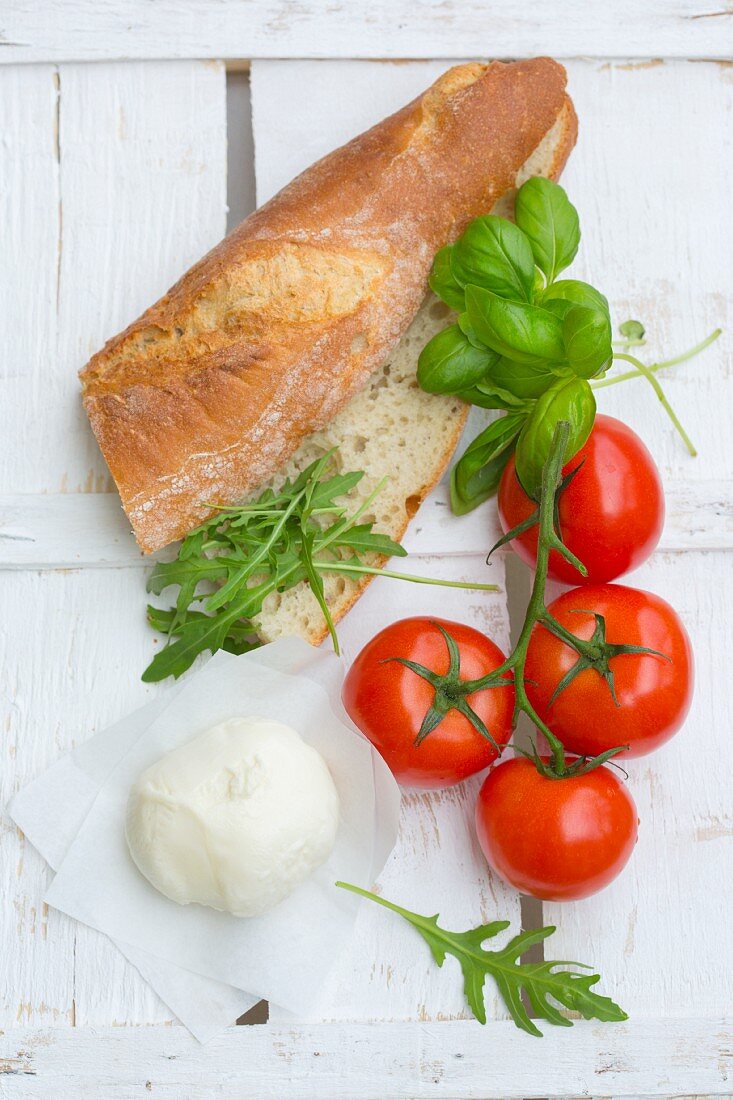 Zutaten für Sandwich mit Mozzarella, Tomaten, Basilikum und Rucola