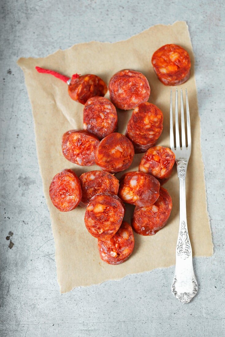 Chorizo slices on a piece of paper with a fork