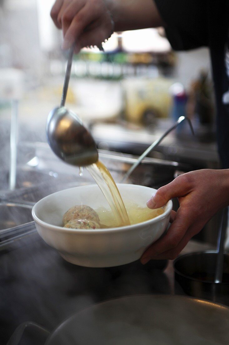 Dumpling soup being ladled into a bowl (South Tyrol)