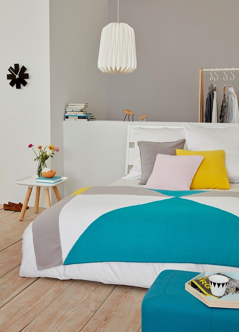 A tangram-style colourful quilt on a double bed