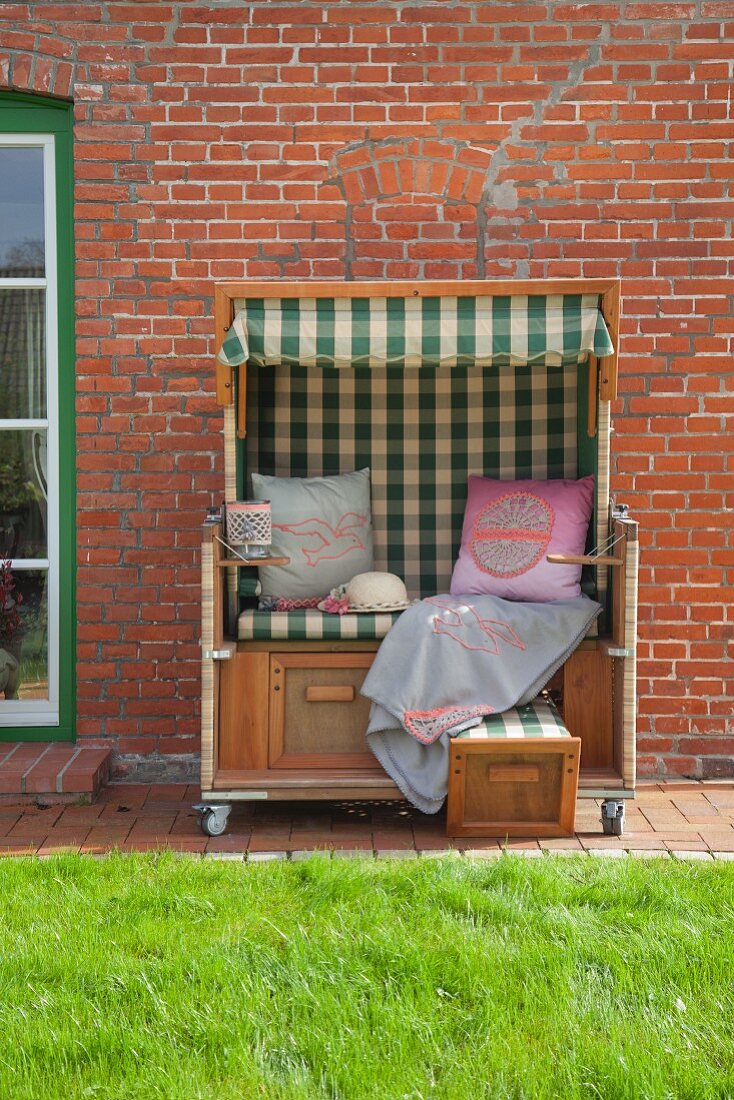 Scatter cushions and blanket in traditional beach chair against brick wall
