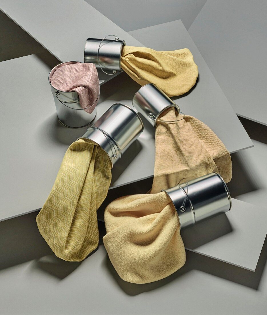 Various fabric swatches in shades of pink and yellow in small metal buckets