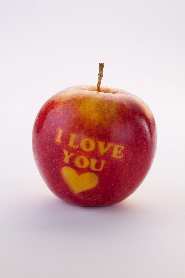 A red apple carved with the words 'I love you' and a heart
