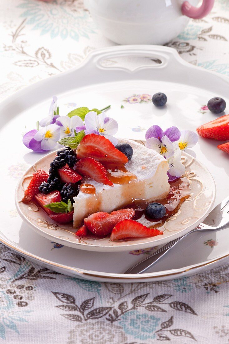 A slice of cheesecake with fresh berries and fruit syrup