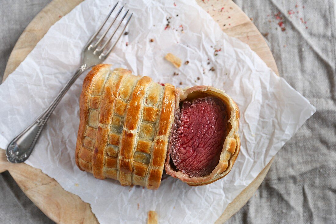 Beef Wellington, sliced, on a piece of paper (seen from above)