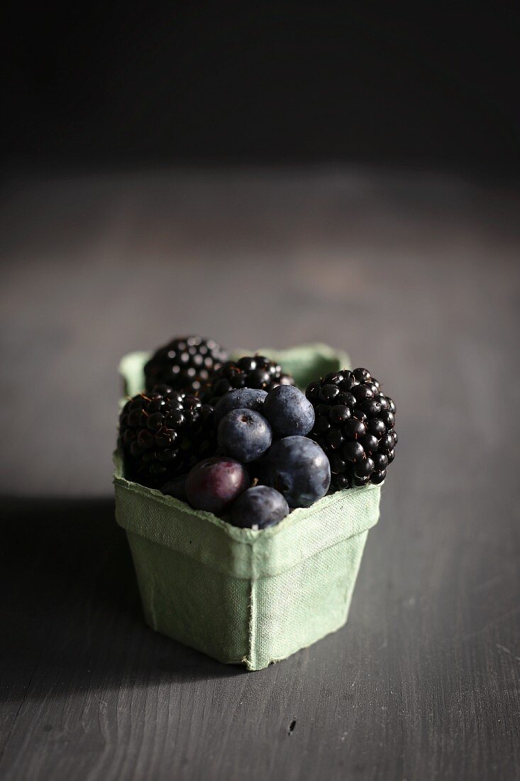 Blueberries and blackberries in an old-fashioned cardboard punnet