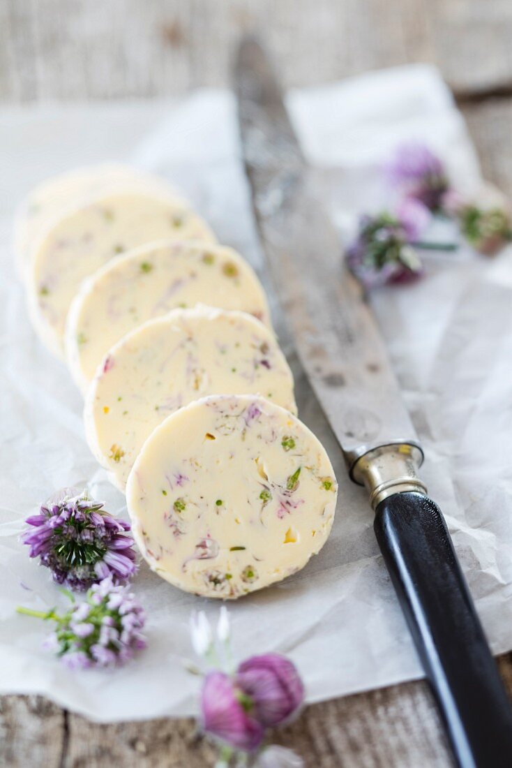 Chive flower butter on a piece of paper with a knife
