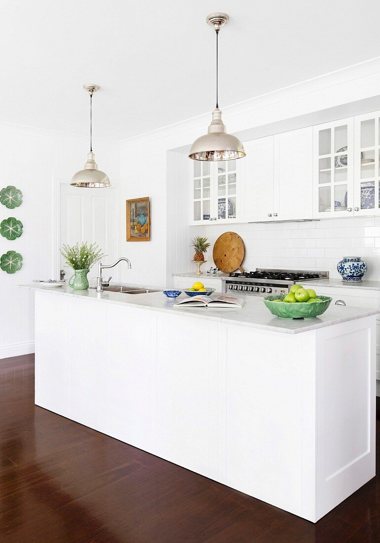 Open white kitchen with kitchen island and two pendant lights