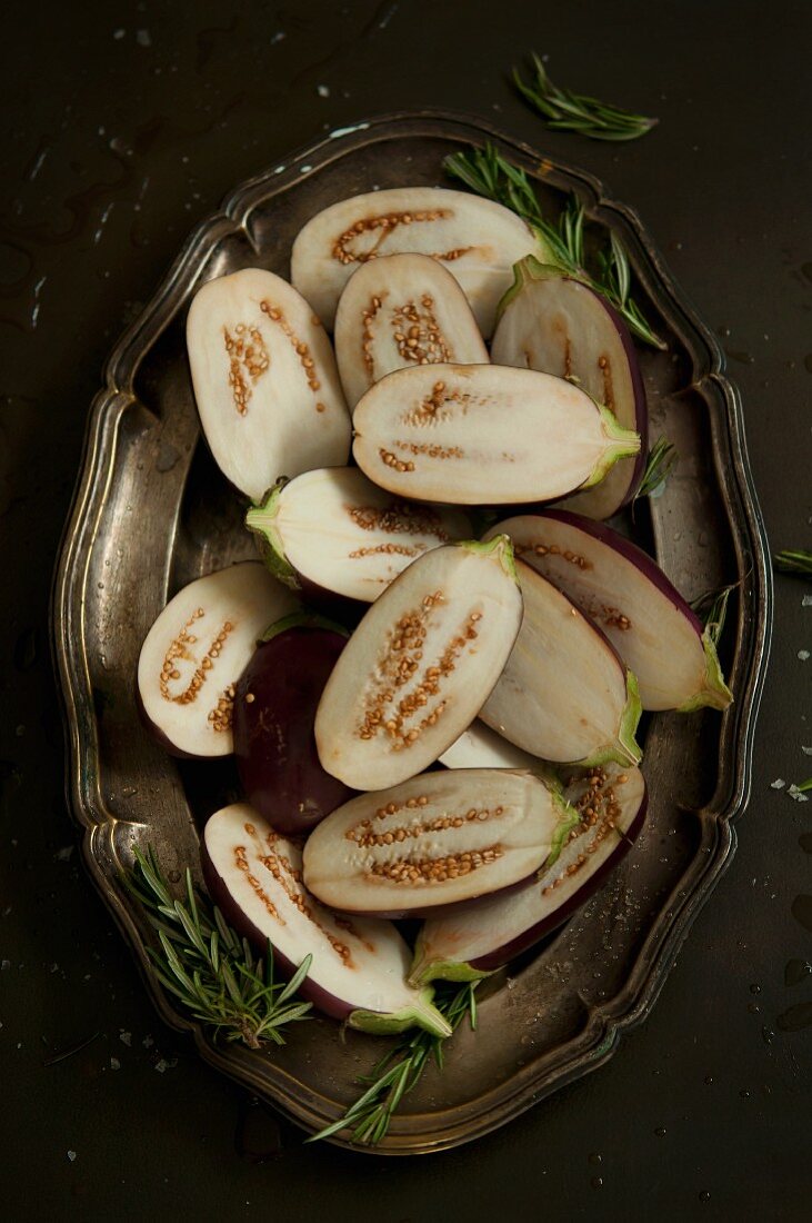 Halved baby aubergines on a silver tray (seen from above)