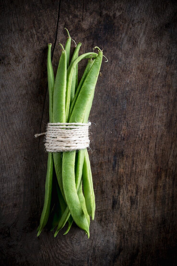 A bundle of green beans on a wooden board