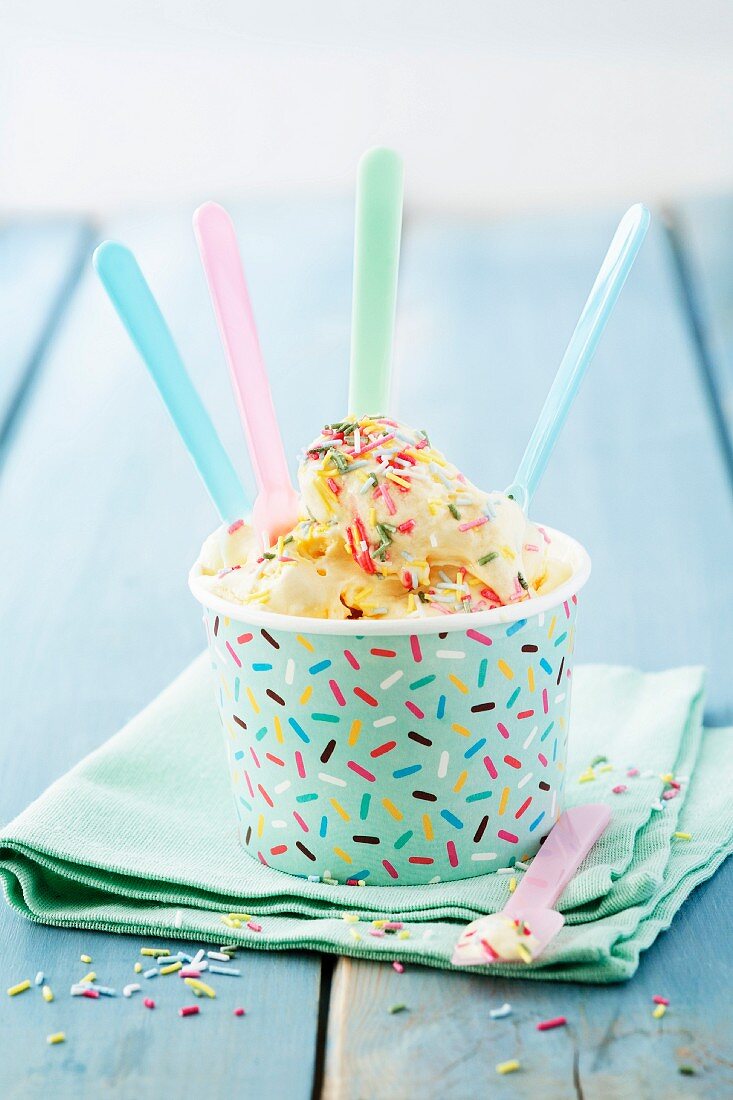 Vanilleeis mit bunten Zuckerstreuseln im Pappbecher mit Eislöffeln