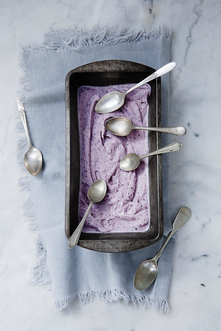 Blueberry ice cream in a loaf tin with silver spoons