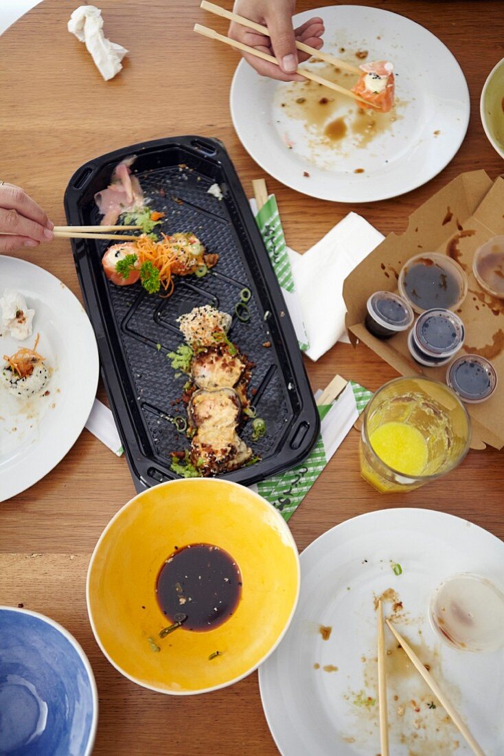 Sushi on table and hands holding chopsticks