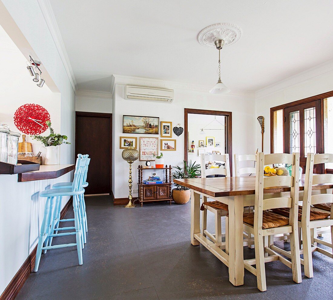 Country-style dining area, light blue bar stools on kitchen counter with red wall clock