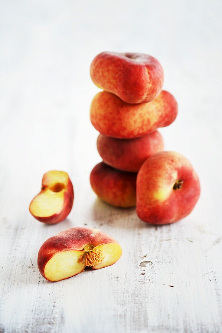 A stack of fresh vineyard peaches next to a halved one