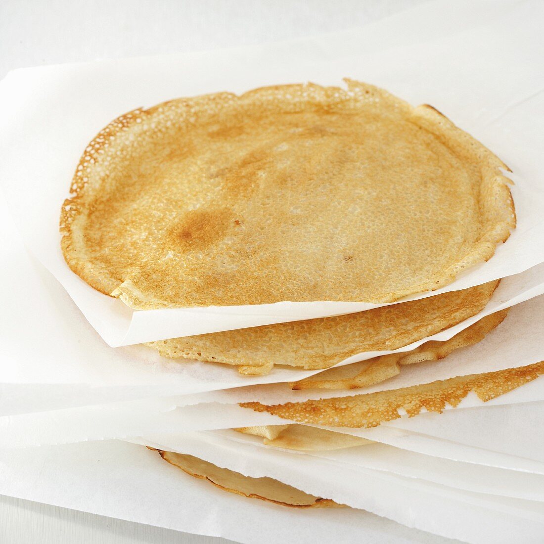 A stack of pancakes separated by sheets of parchment paper