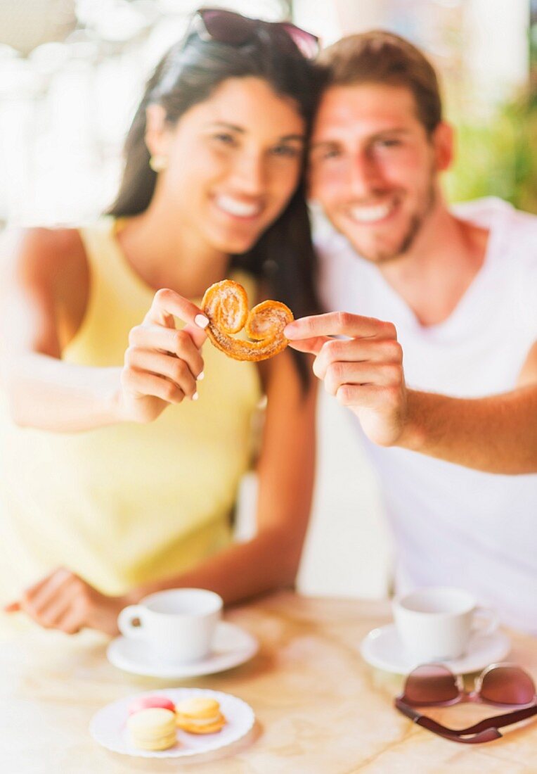 A couple in a cafe sharing a biscuit