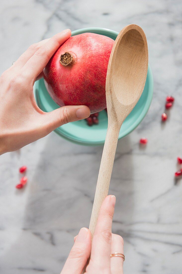 Granatapfel wird mit Holzkochlöffel geöffnet