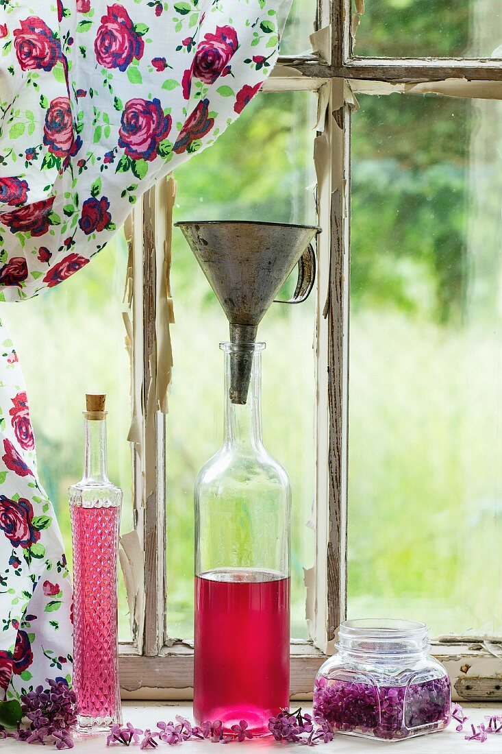 Bottles of homemade lilac syrup on a windowsill