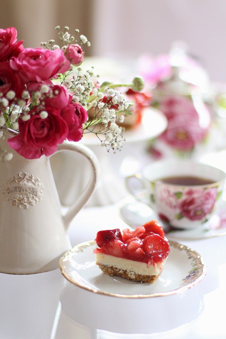 A slice of strawberry cake on a romantically laid table