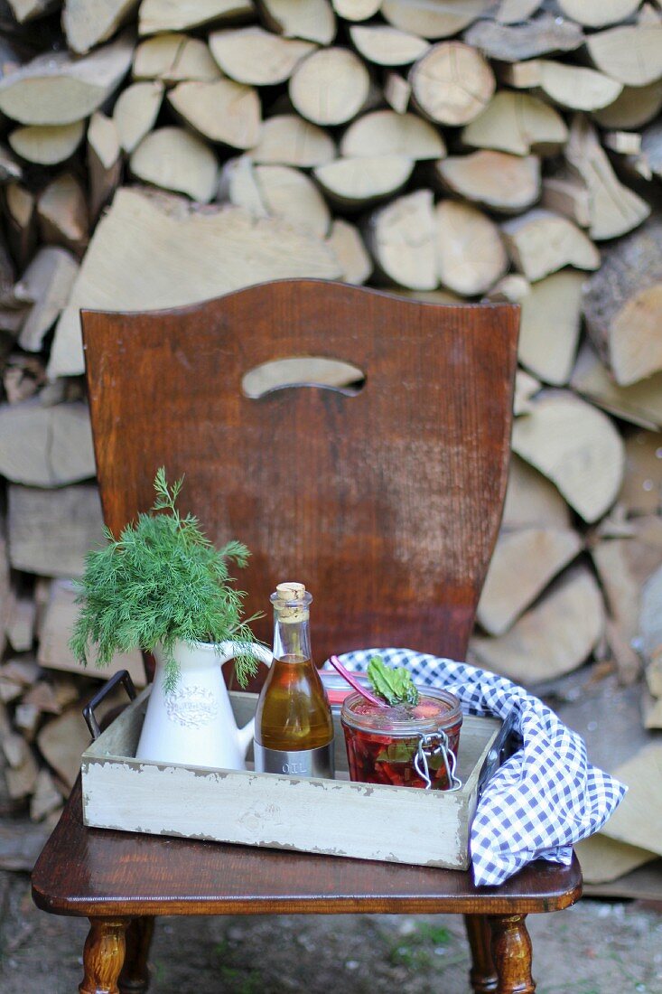 Bügelglas mit Suppe, Ölflasche und Dill auf Holzstuhl im Freien