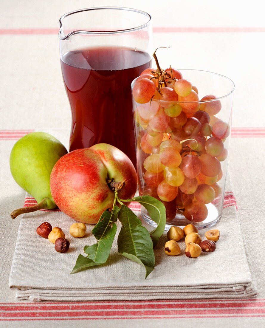 An arrangement of fresh fruit, hazelnuts and red wine