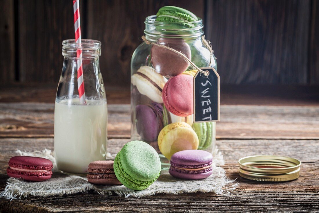 Bunte Macarons im Vorratsglas und daneben mit Milchflasche