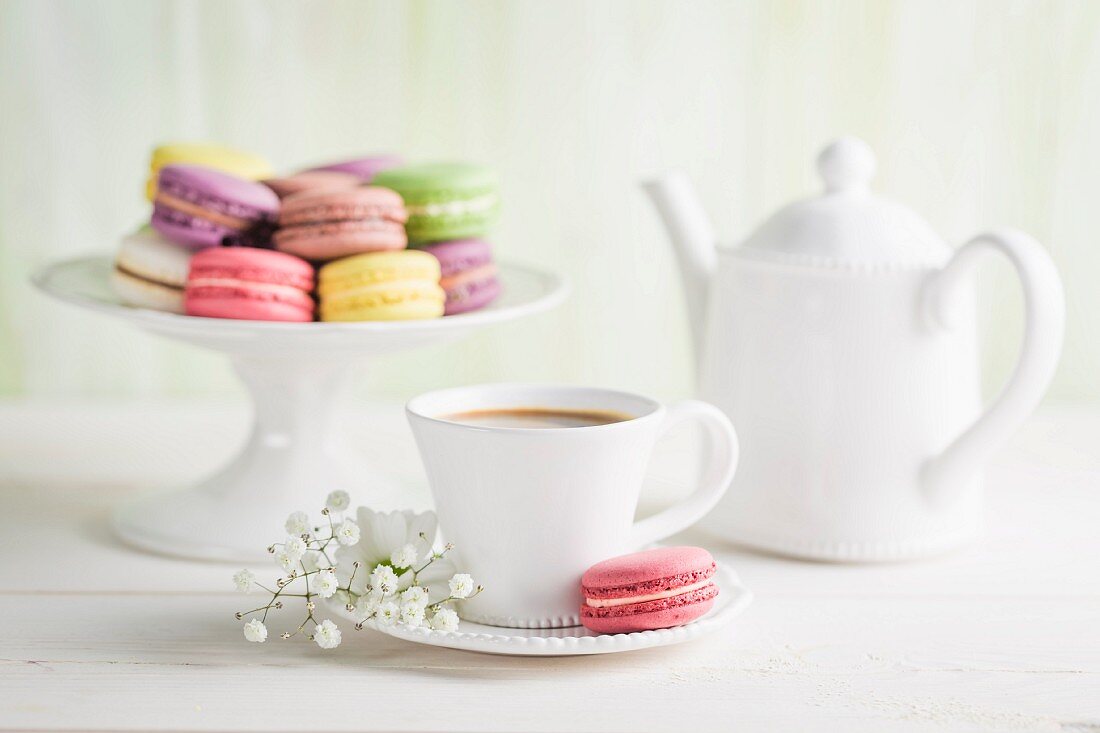 Bunte Macarons mit Kaffee auf weißem Tisch