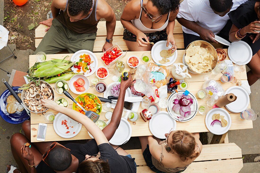 Blick von Oben auf Gruppe von jungen Leuten an gedecktem Tisch im Hinterhof sitzend