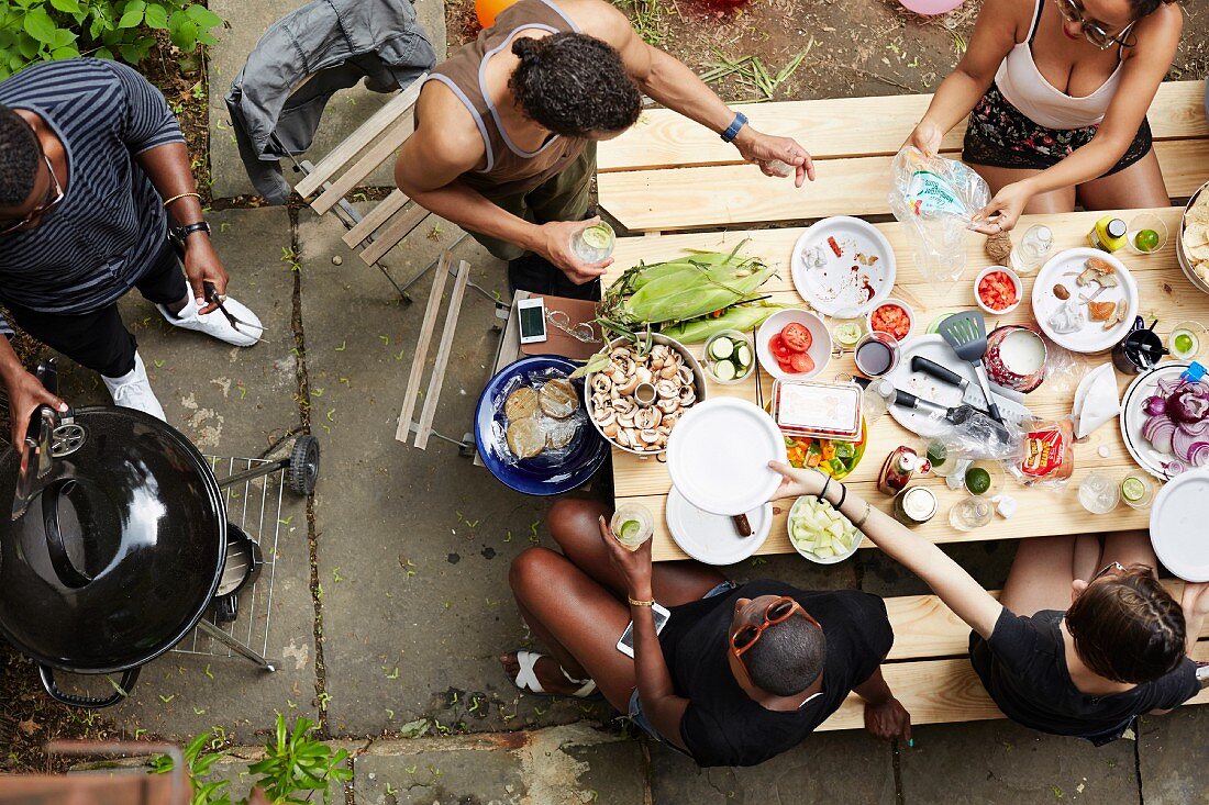 Blick von Oben auf Gruppe von jungen Leuten beim Grillen im Hinterhof