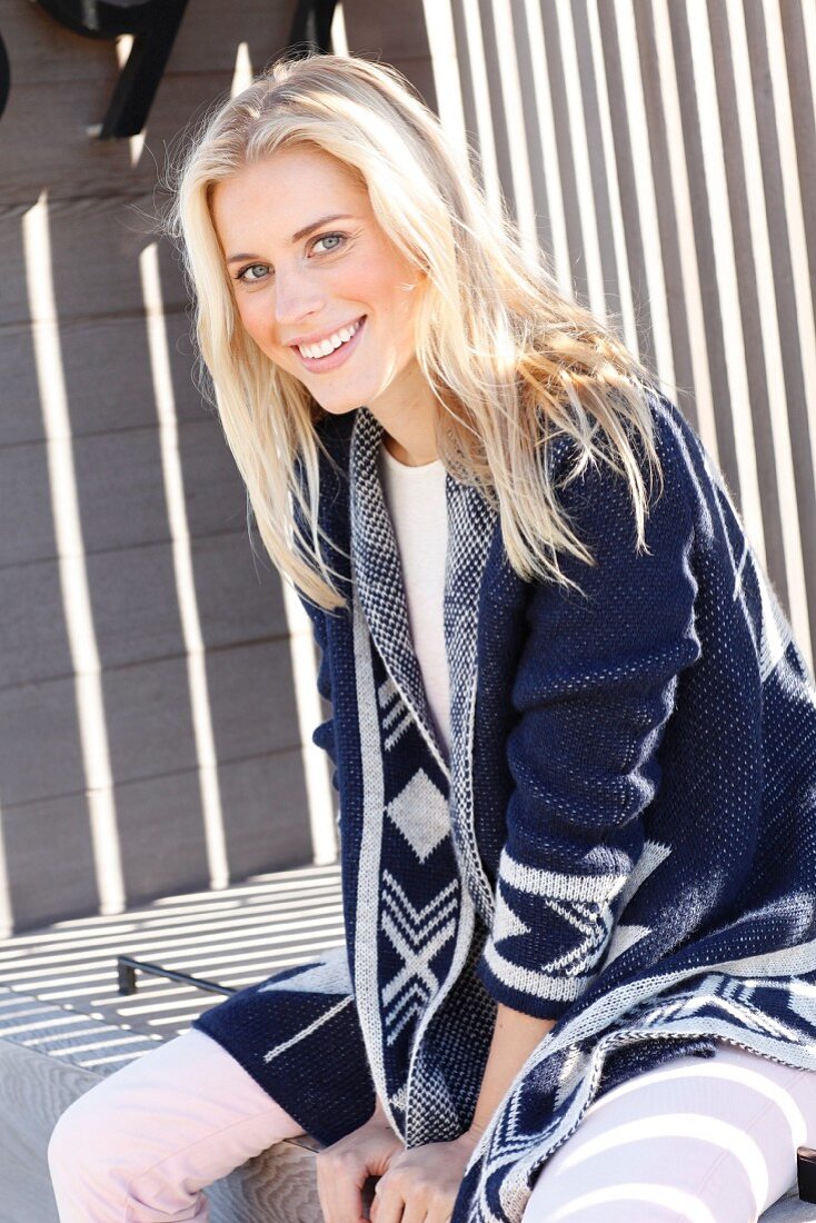 A young blonde woman wearing a top and a blue-and-white cardigan