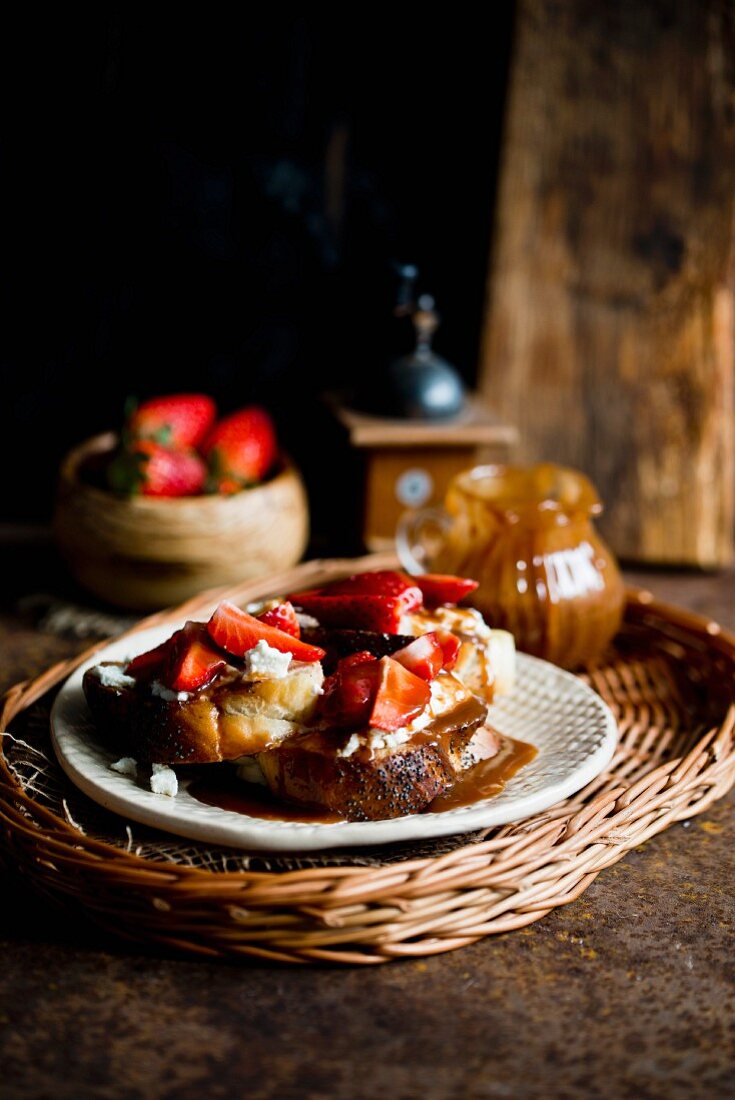 A slice of white bread topped with cream cheese, strawberries and caramel sauce