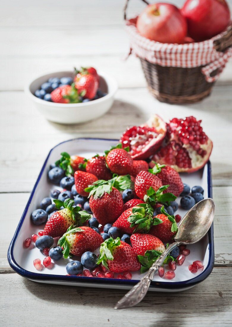 Fresh strawberries, blueberries and pomegranate on an enamel baking tray