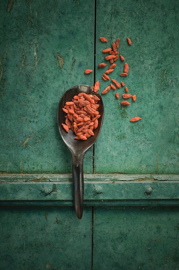 Goji berries on a spoon on a rustic surface