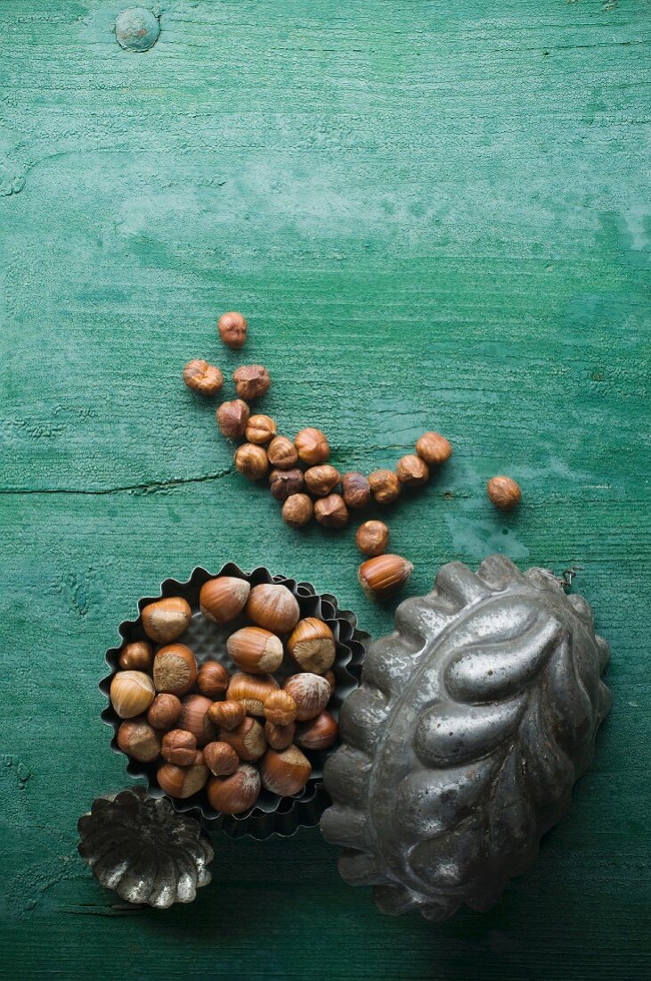 Hazelnuts, shelled and unshelled, in a baking tin on a rustic wooden surface
