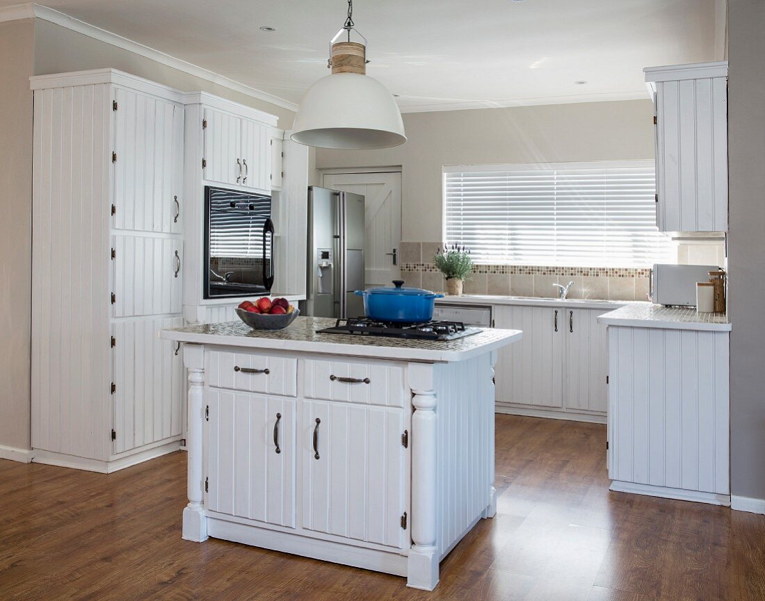Country-house kitchen with white wooden cupboards and island counter