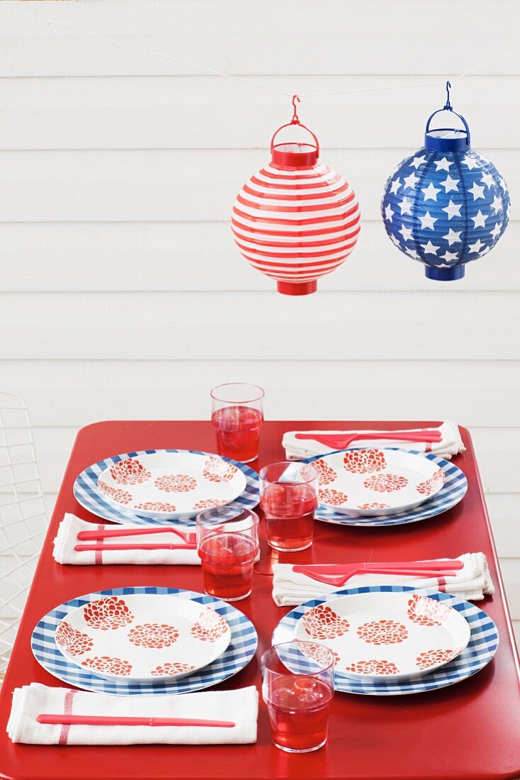 Outdoor table set for Fourth of July below paper lanterns (USA)