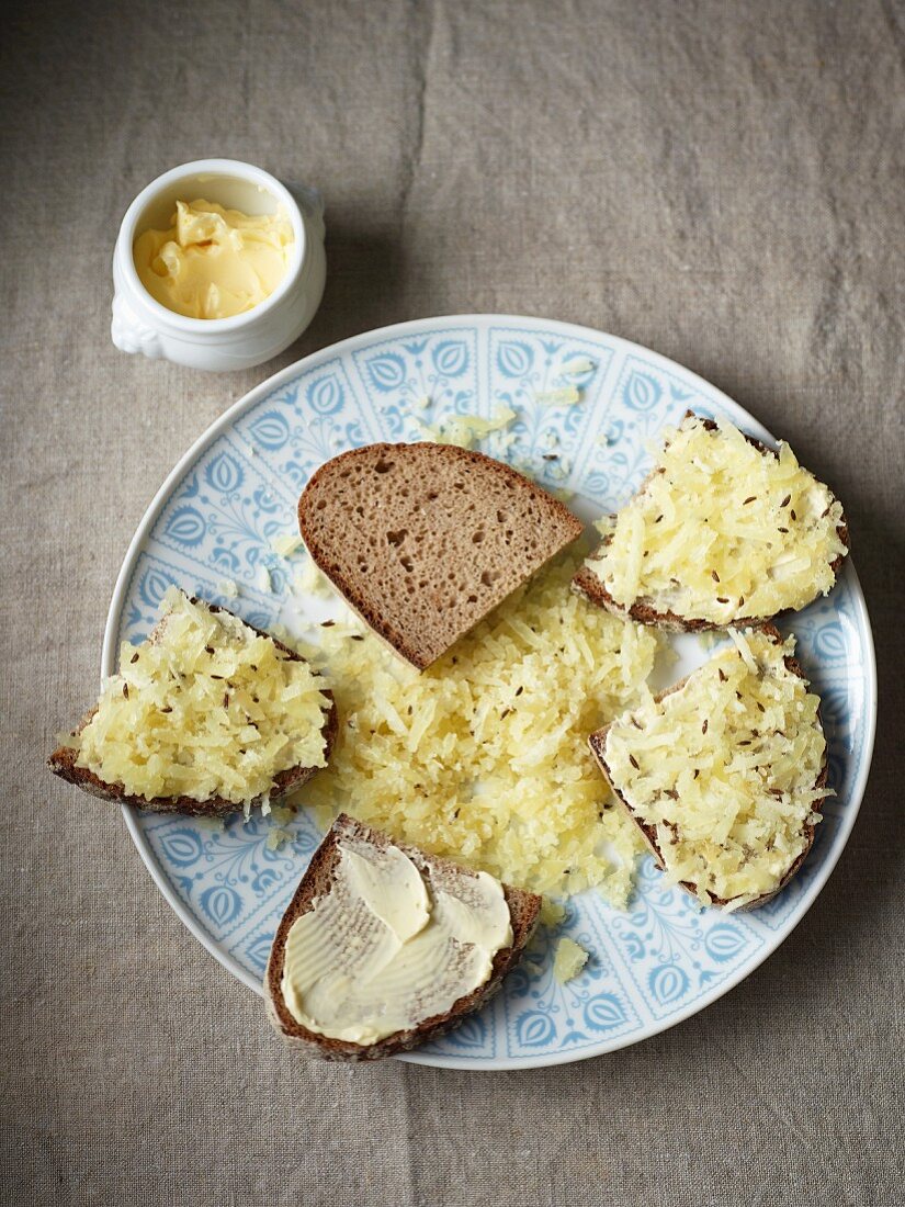 Slices of bread topped with cheese, butter and caraway