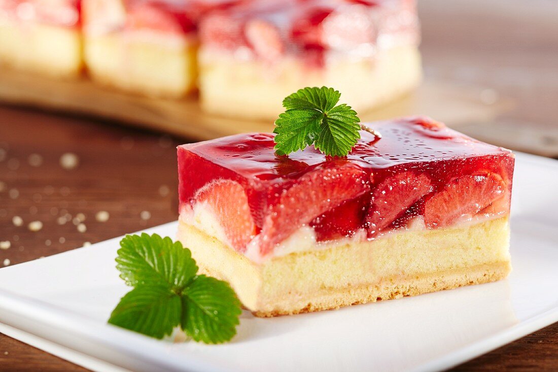 A slice of strawberry cake garnished with a strawberry leaf