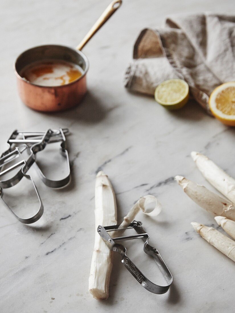 White asparagus with a peeler and a saucepan of brown butter