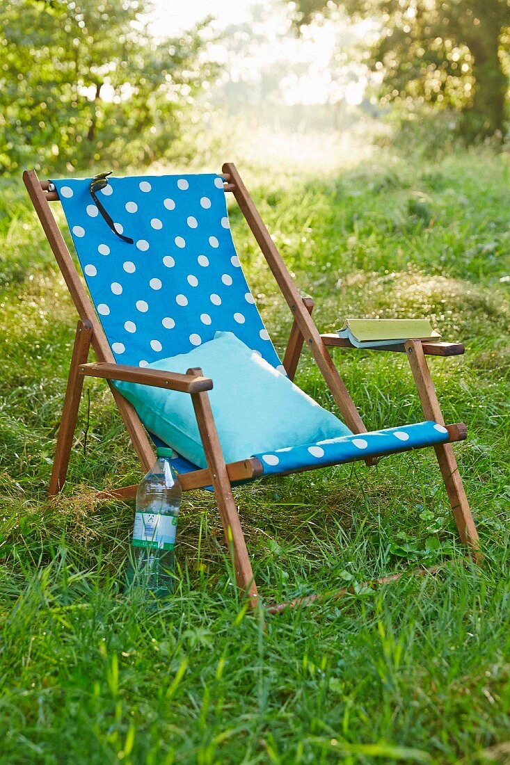 A deckchair with homemade fabric cover on green grass in a garden