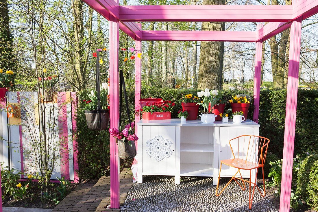 Pinkfarbene Pergola und eine Anrichte im Garten