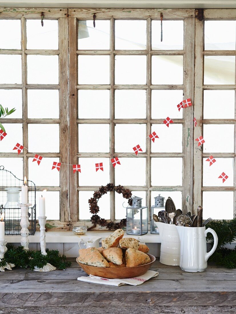 Selbstgebackene Kräuterbrötchen in Holzschale vor Küchenfenster