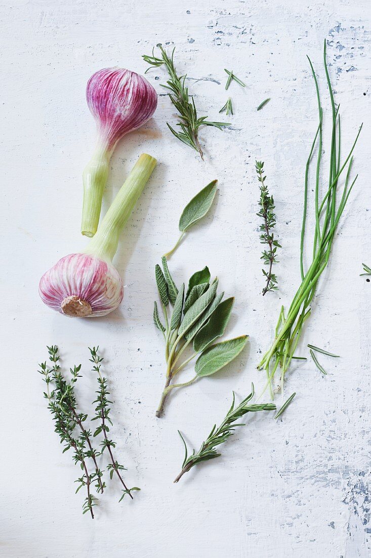 An arrangement of fresh garlic and various herbs