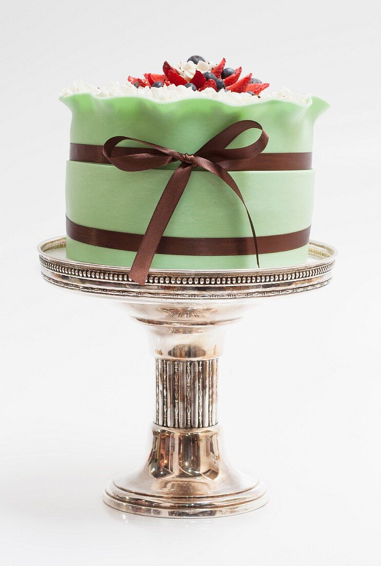 A green wedding cake on a silver cake stand