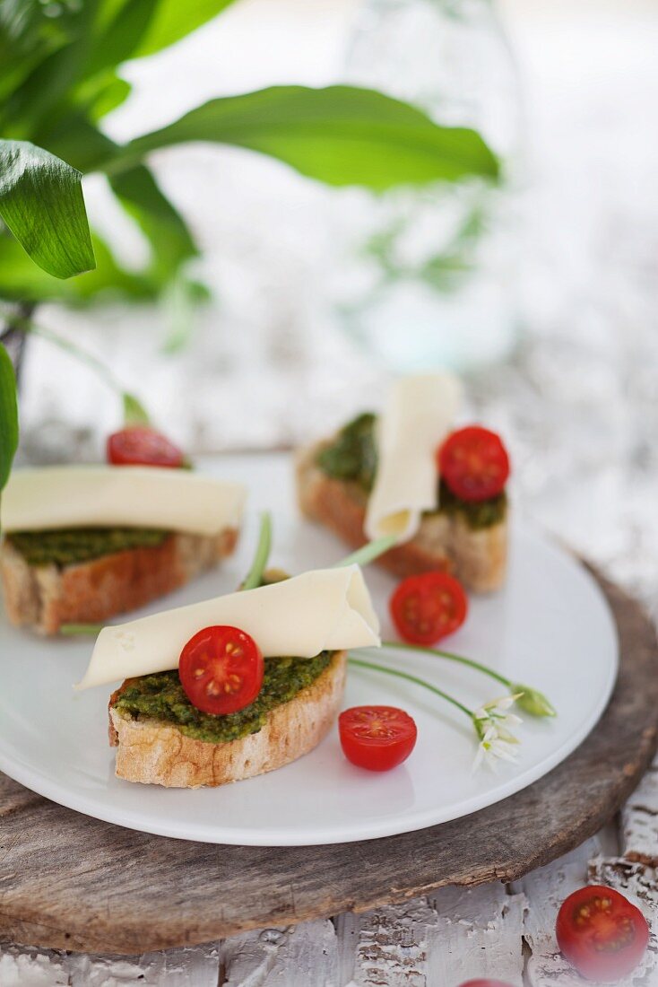 Slices of baguette topped with wild garlic pesto, cheese and cocktail tomatoes