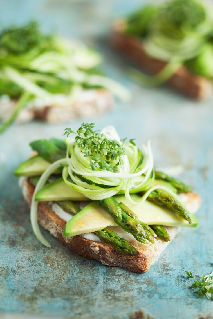 Grilled bread topped with avocado, green asparagus and cress