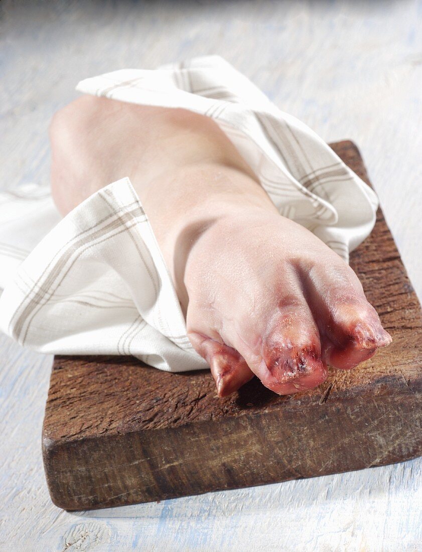 A pig's trotter on a wooden board