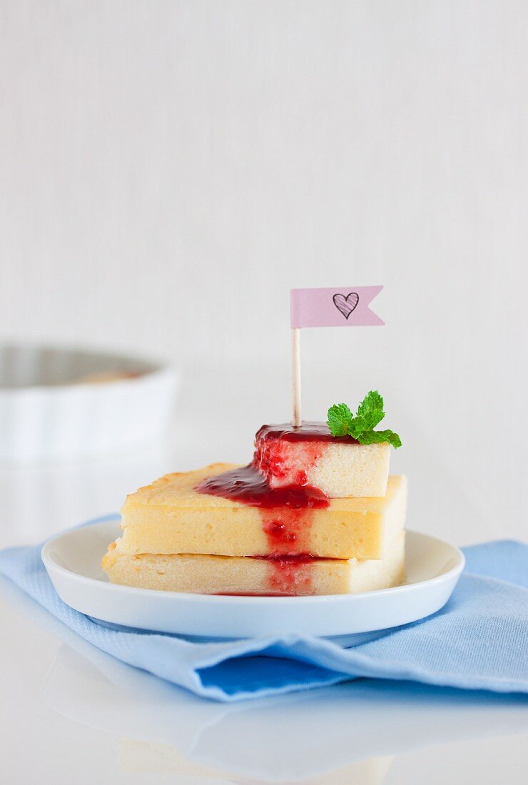 A stack of quark and semolina slices with raspberry sauce and mint leaves